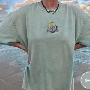 Person wearing a bay Mountain Moon and Book Embroidered T-Shirt