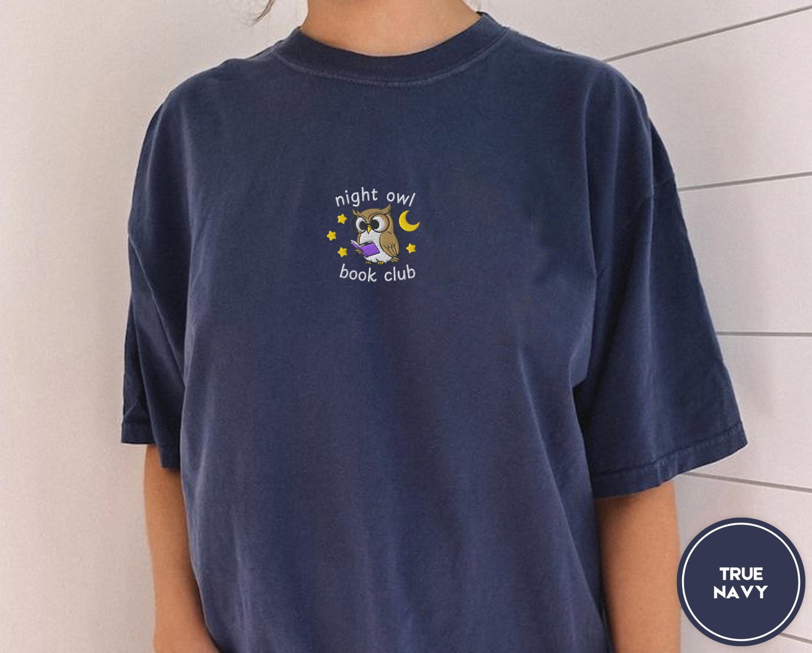 Person wearing a true navy Night Owl Book Club Embroidered T-Shirt