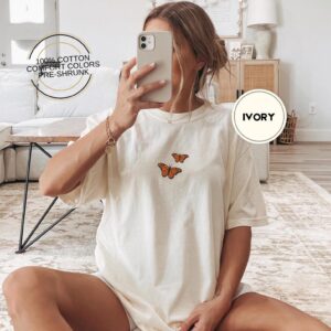 Person wearing an ivory Orange Butterflies Embroidered T-Shirt
