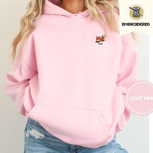Person wearing a light pink Playful Foxes Embroidered Hoodie