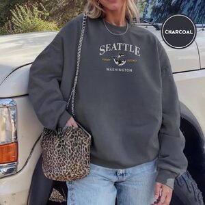 Person wearing a charcoal Puget Sound Orca Duo Embroidered Sweatshirt