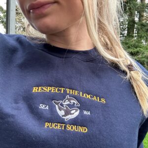Person wearing a navy Puget Sound Orcas Embroidered Sweatshirt