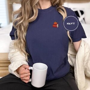 Person wearing a navy Pumpkin Book Stack Embroidered T-Shirt