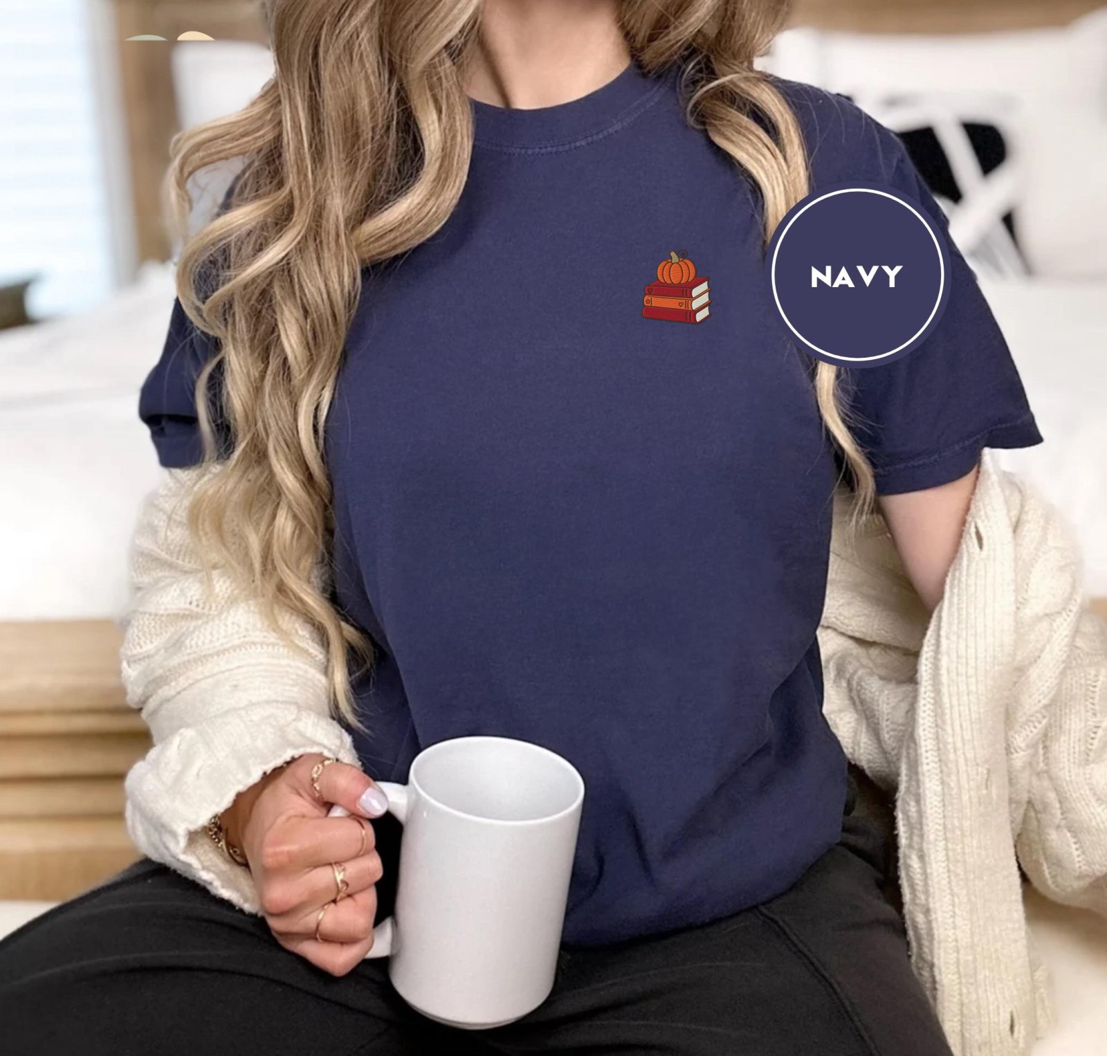 Person wearing a navy Pumpkin Book Stack Embroidered T-Shirt