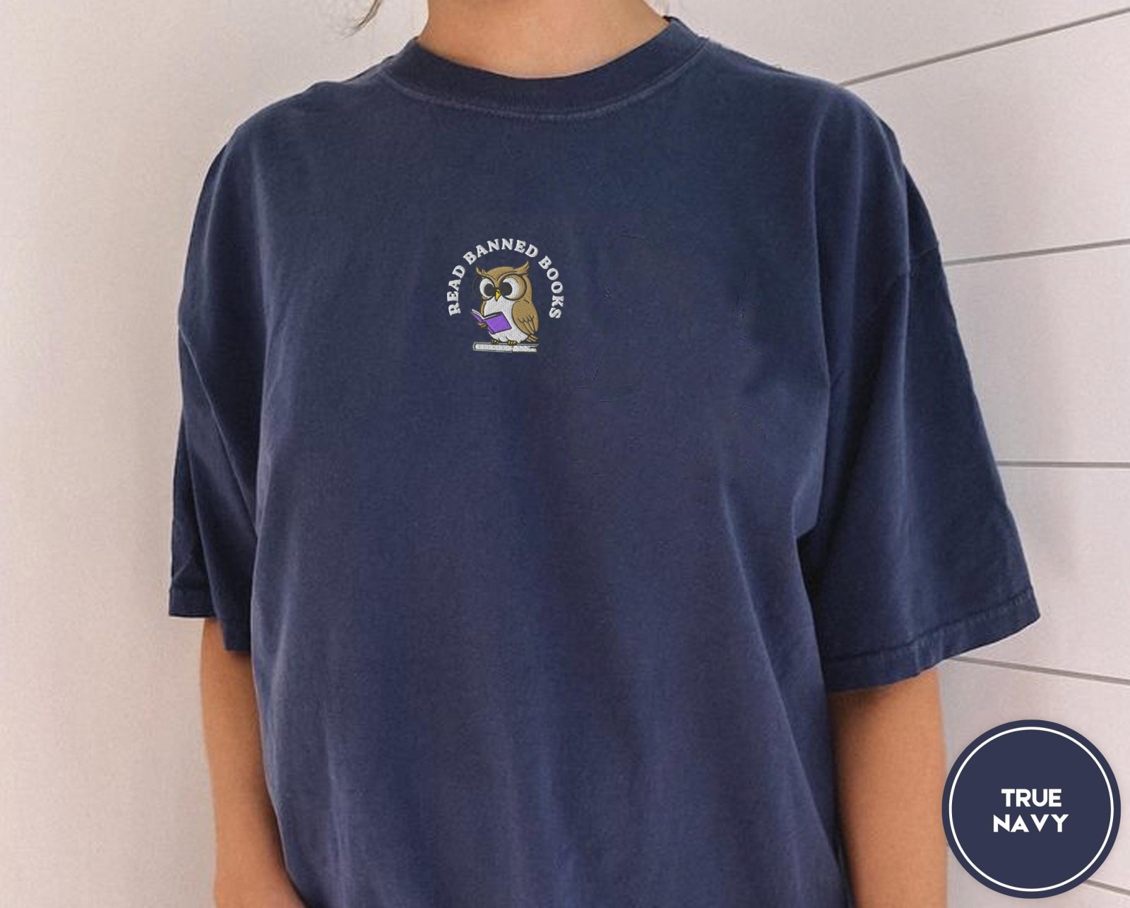 Person wearing a true navy Read Banned Books Owl Embroidered T-Shirt
