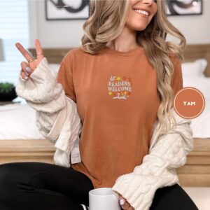 Person wearing a yam Readers Welcome Floral Book Embroidered T-Shirt