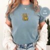 Person wearing an ice blue Reading Teddy Bear Embroidered T-Shirt