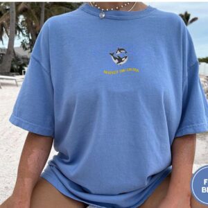Person wearing a flo blue Respect the Locals Orca Embroidered T-Shirt
