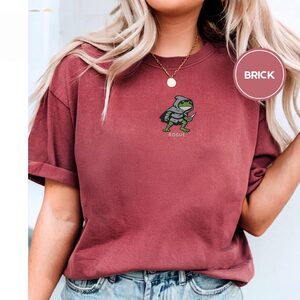 Person wearing a brick Rogue Frog Embroidered T-Shirt