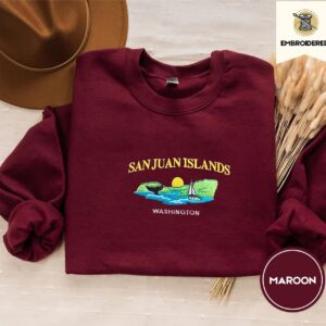 Maroon crewneck sweatshirt embroidered with San Juan Islands, Washington, an orca tail, a sailboat and a setting sun
