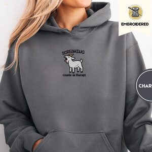 Person wearing a charcoal Screaming Goat Embroidered Hoodie