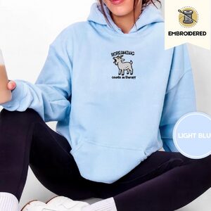 Person wearing a light blue Screaming Goat Embroidered Hoodie
