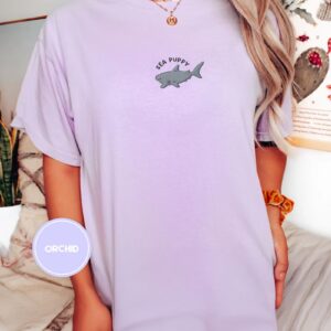 Person wearing an orchid Sea Puppy Shark Embroidered T-Shirt
