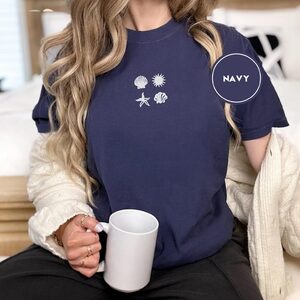 Person wearing a navy Seashells Sun and Starfish Embroidered T-Shirt