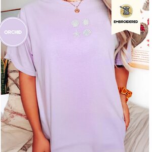 Person wearing an orchid Seashells Sun and Starfish Embroidered T-Shirt