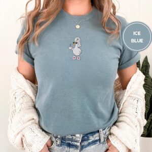 Person wearing an ice blue Self-Care Goose Embroidered T-Shirt