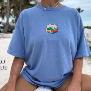 Person wearing a flo blue Sleeping Cat on Books Embroidered T-Shirt