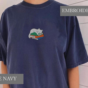 Person wearing a true navy Sleeping Cat on Books Embroidered T-Shirt