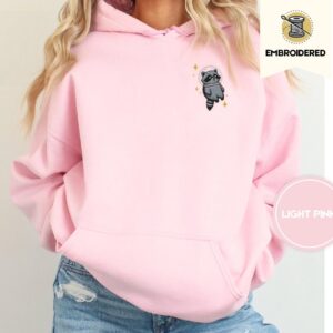 Person wearing a light pink Space Raccoon Embroidered Hoodie
