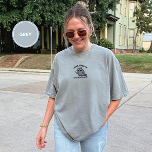Person wearing a grey Stability Raccoon Embroidered T-Shirt