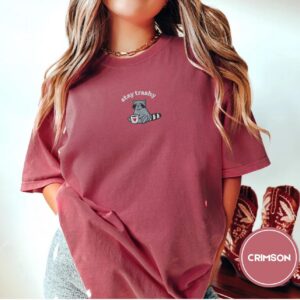 Person wearing a crimson Stay Trashy Raccoon Embroidered T-Shirt