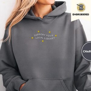 Person wearing a charcoal Support Your Local Library Embroidered Hoodie