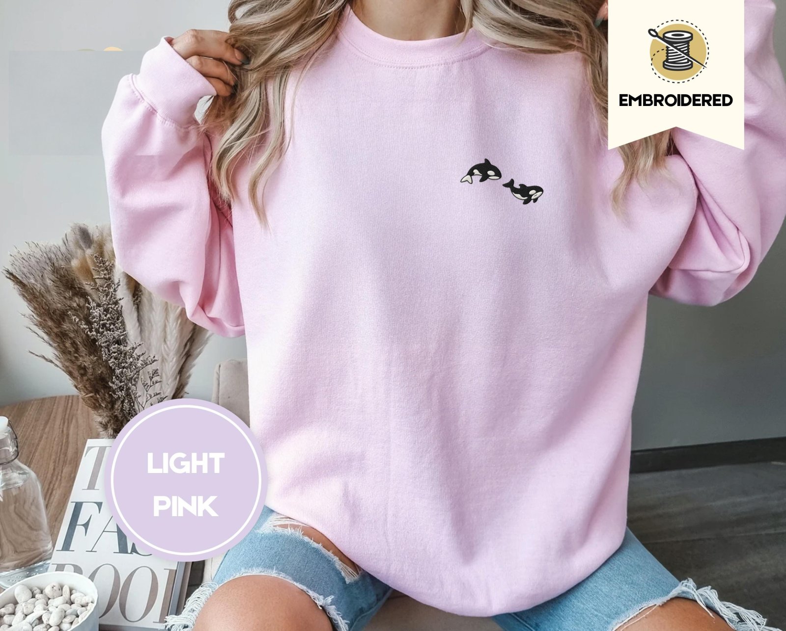 Person wearing a light pink Swimming Orcas Embroidered Sweatshirt