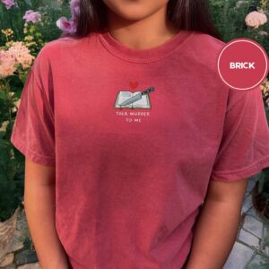 Person wearing a brick Talk Murder to Me Embroidered T-Shirt
