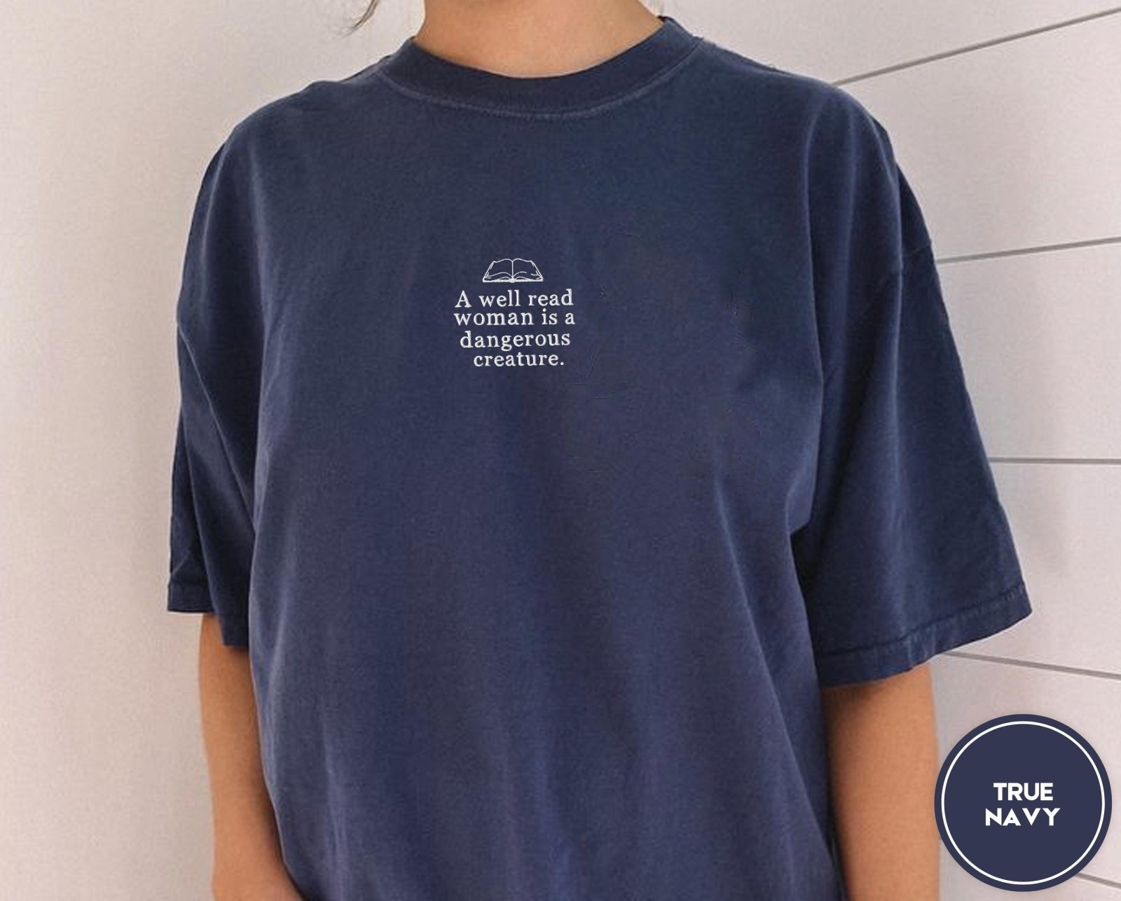 Person wearing a true navy Well Read Woman Quote Embroidered T-Shirt