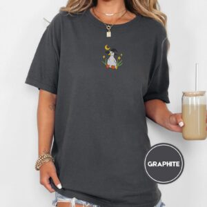Person wearing a graphite Witchy Duckling Embroidered T-Shirt