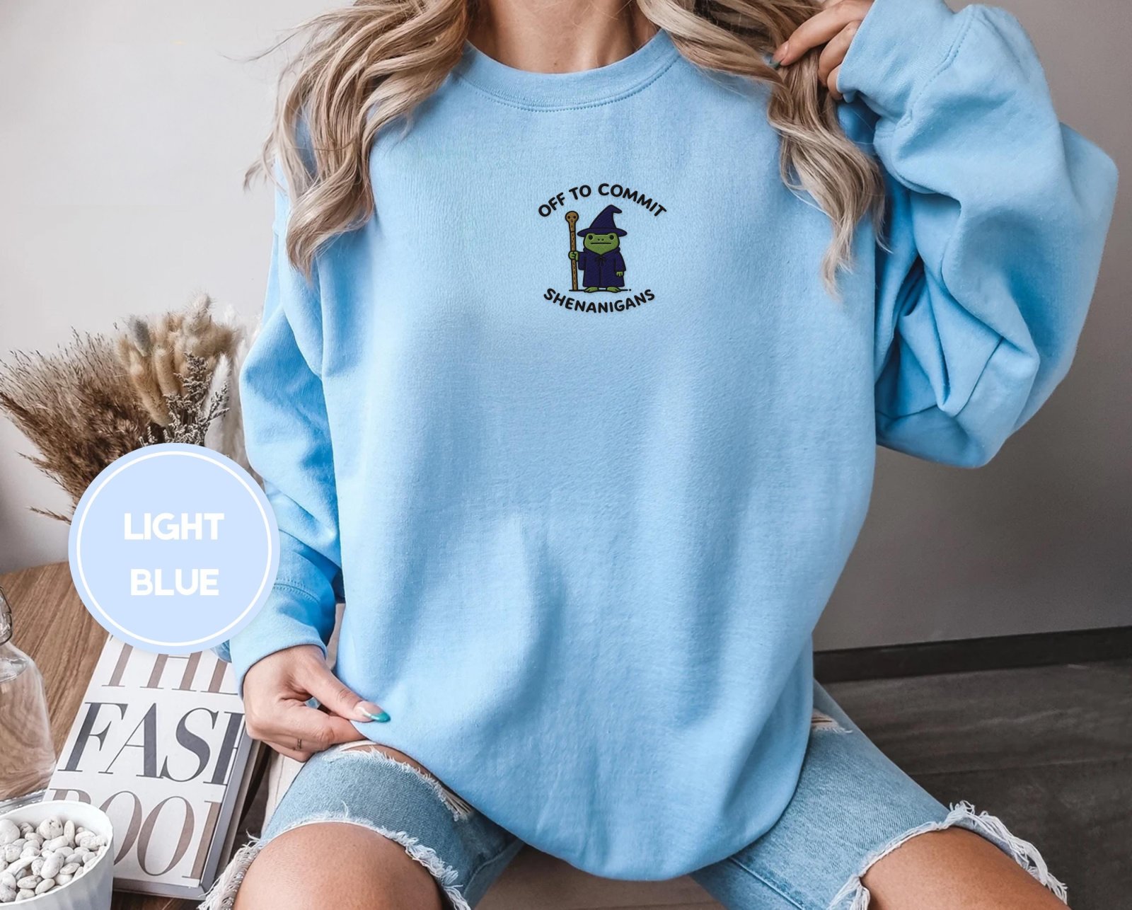 Person wearing a light blue Wizard Frog Embroidered Sweatshirt