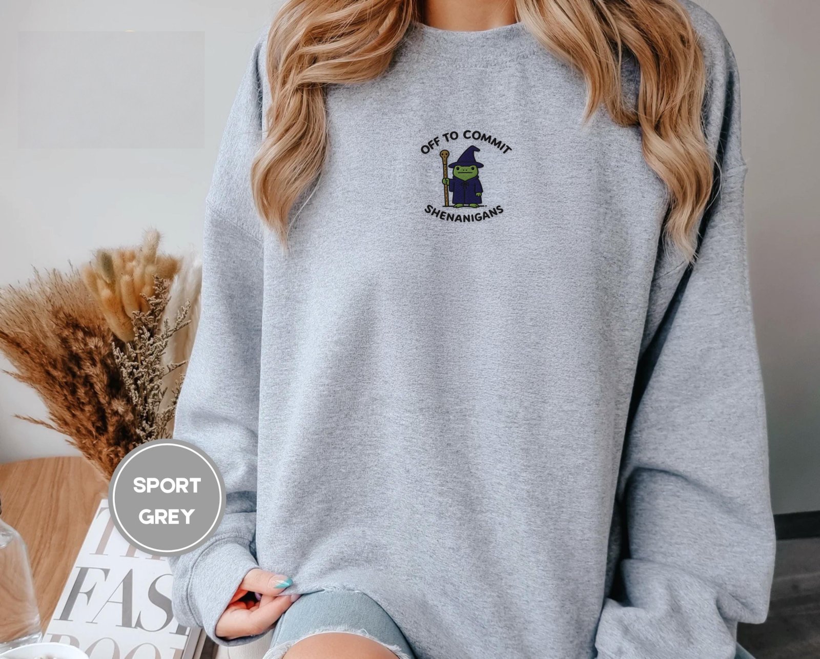 Person wearing a sport grey Wizard Frog Embroidered Sweatshirt