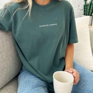 Person wearing a blue spruce Written By A Woman Embroidered T-Shirt